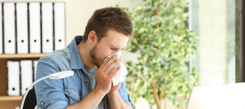 man sneezing into tissue due to poor indoor air quality