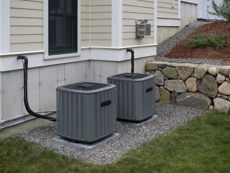 two gray outdoor hvac units on the side of a San Antonio home
