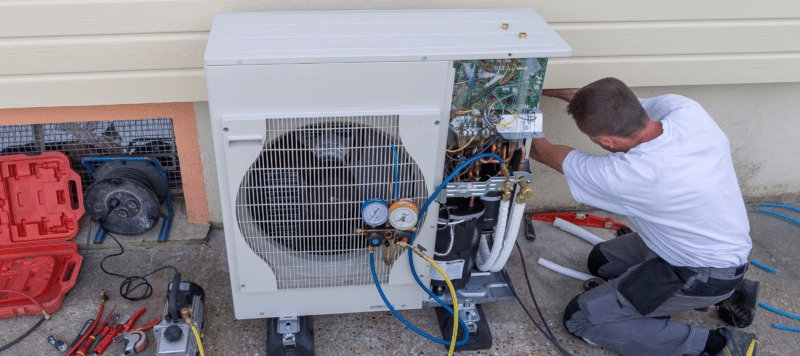 technician performing repairs on a heat pump