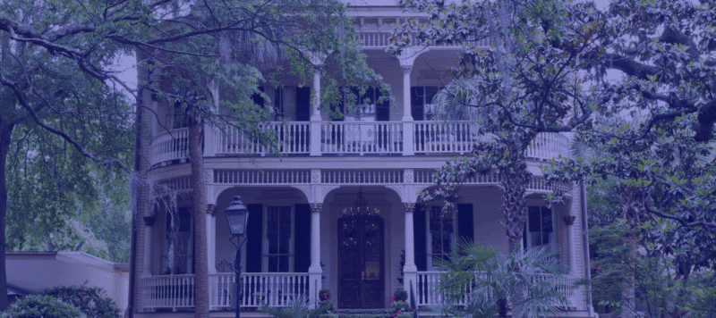 : Historic Southern-style home with large porches and lush trees surrounding the property