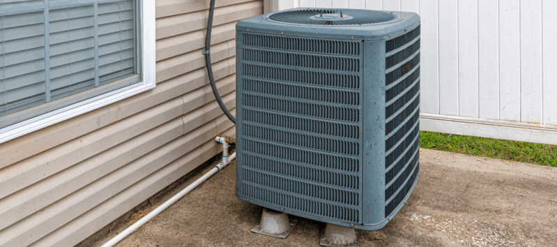 Central air conditioning condenser unit outside a residential home