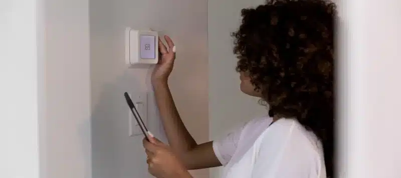 Young woman uses mobile app to adjust or program her new home's temperature